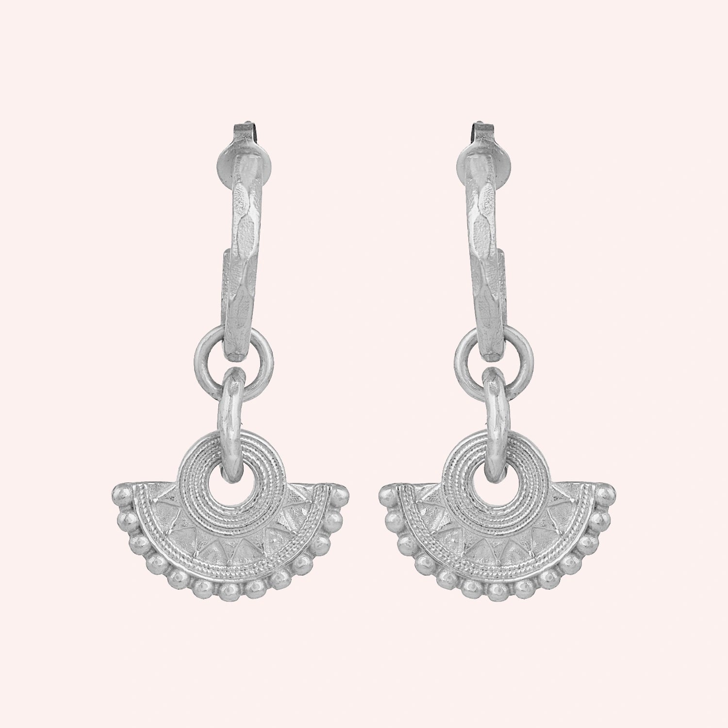 Handmade_earrings_in_sterling_silver_with_handcrafted_design_hoops_at_front_angle_on_solid_pink_background
