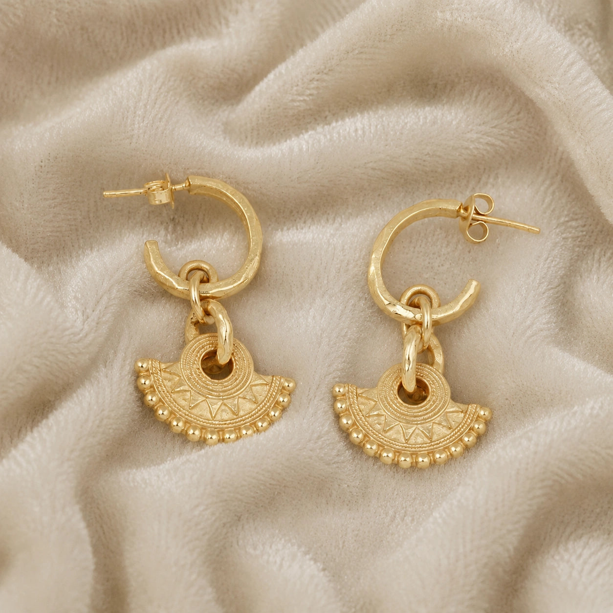 Handmade_earrings_in_gold_plated_silver_with_handcrafted_design_hoops_at_slight_angle_on_soft_fabric_background