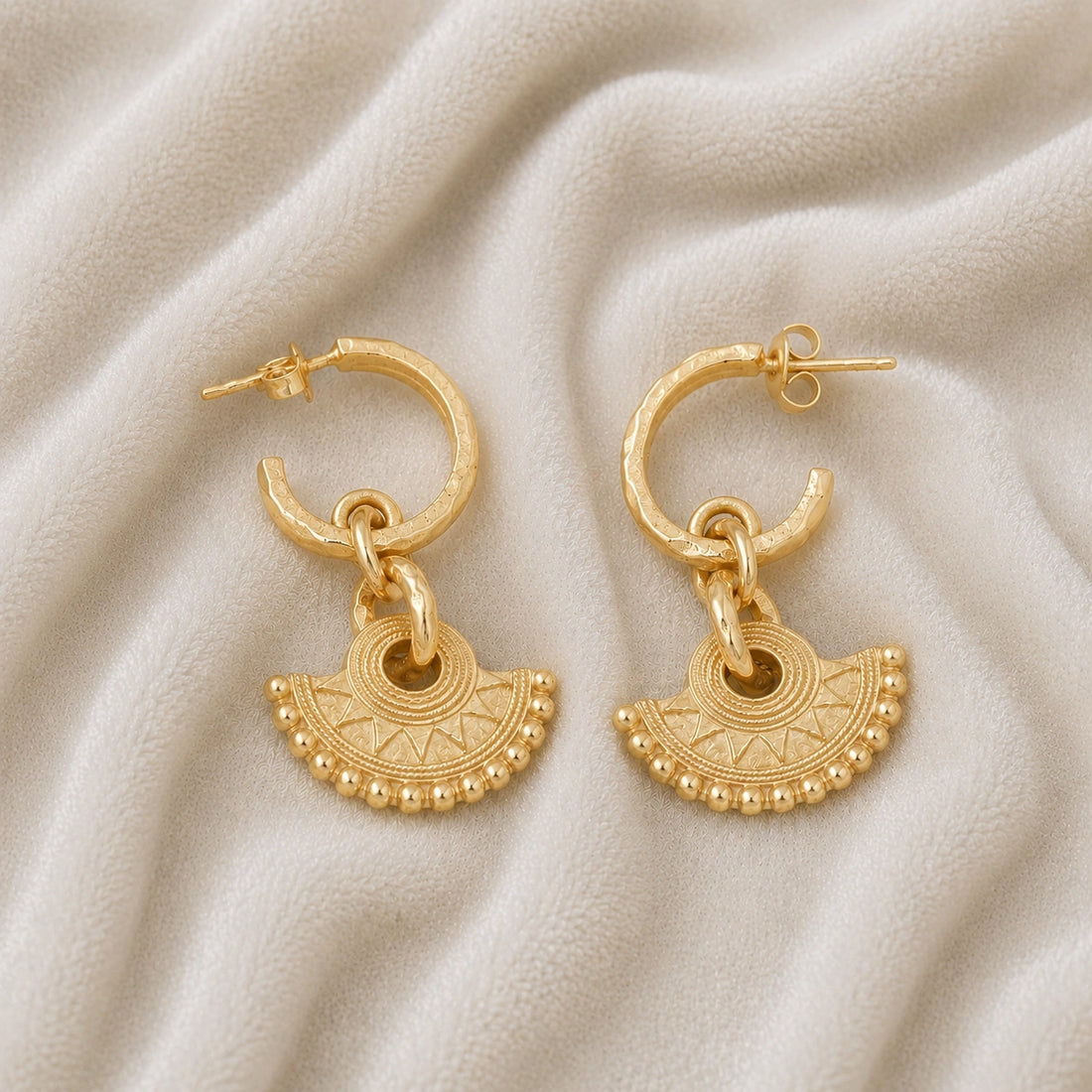 Handmade_earrings_in_gold_plated_silver_with_handcrafted_design_hoops_at_front_angle_on_soft_fabric_background