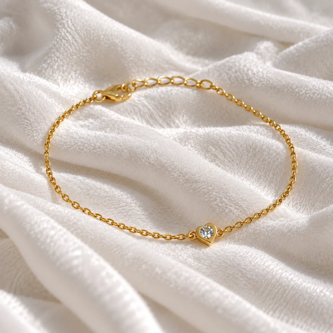 Heart_bracelet_in_gold_plated_silver_with_a_small_lab_grown_diamond_at_slight_angle_view_on_soft_fabric_background