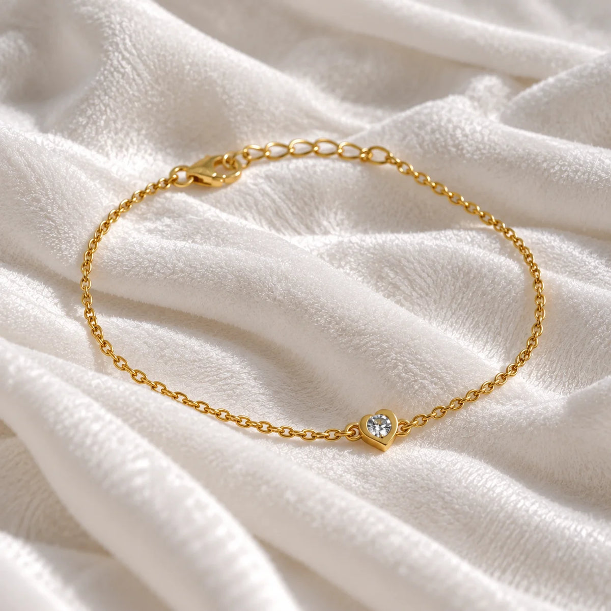 Heart_bracelet_in_gold_plated_silver_with_a_small_lab_grown_diamond_at_slight_angle_view_on_soft_fabric_background