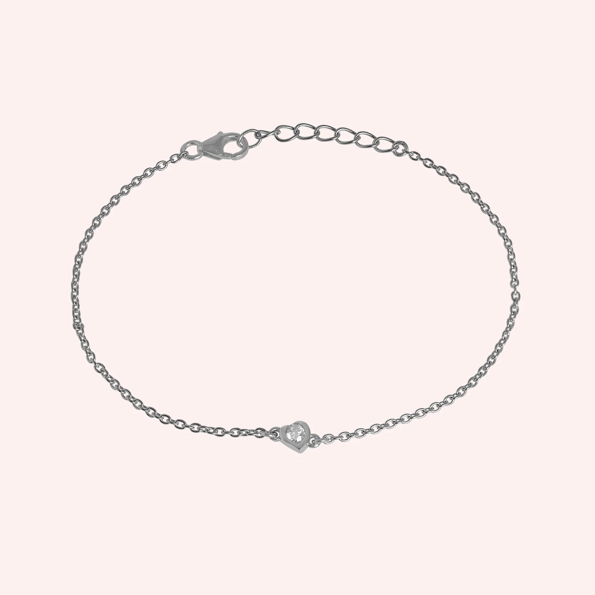 Heart_bracelet_in_sterling_silver_with_a_small_CZ_stone_at_front_angle_view_on_solid_pink_background