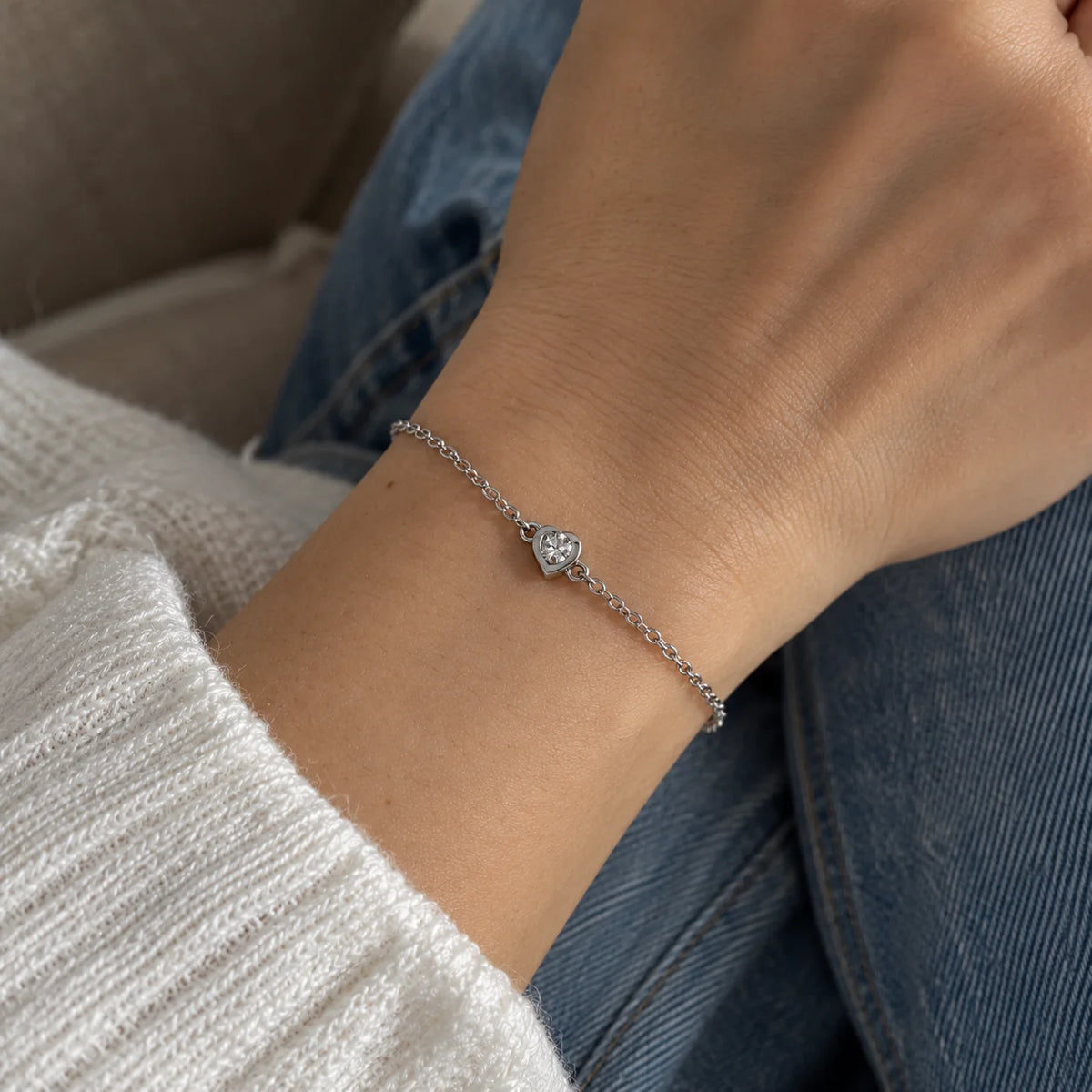 Heart_bracelet_in_sterling_silver_with_a_small_CZ_stone_at_front_angle_view_worn_by_a_model