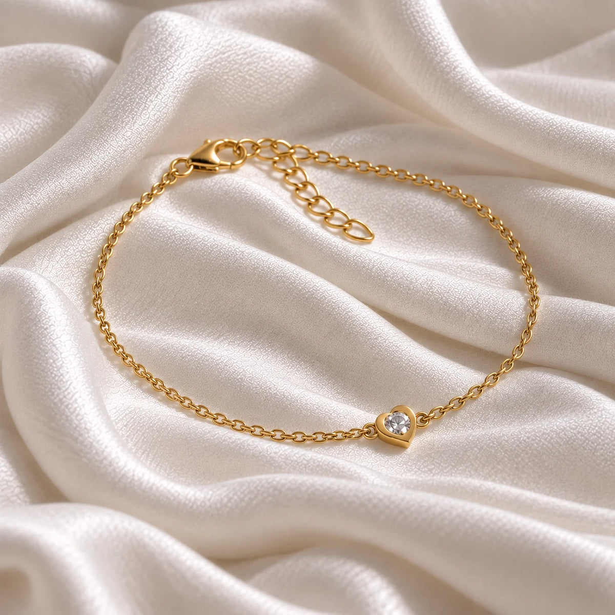 Heart_bracelet_in_gold_plated_silver_with_a_small_CZ_stone_at_side_angle_view_on_soft_fabric_background