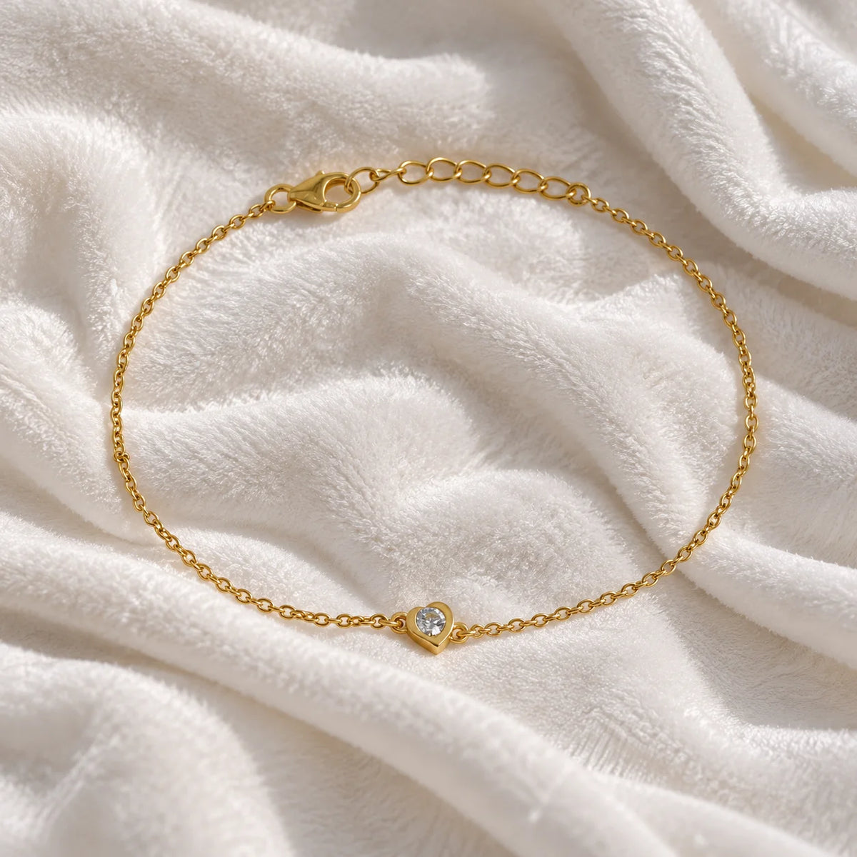 Heart_bracelet_in_gold_plated_silver_with_a_small_lab_grown_diamond_at_front_angle_view_on_soft_fabric_background