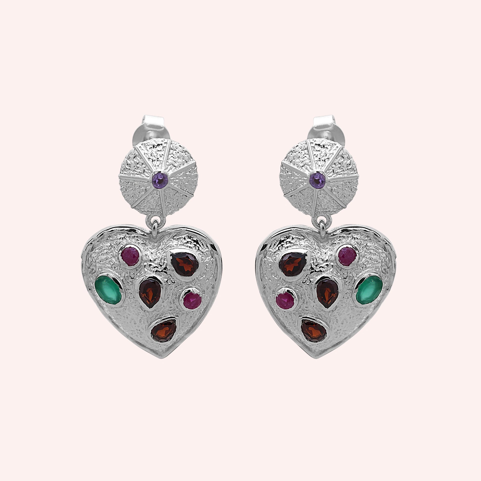 Heart_earrings_in_sterling_silver_with_garnet_ruby_and_green_onyx_stones_in_front_angle_on_solid_pink_background