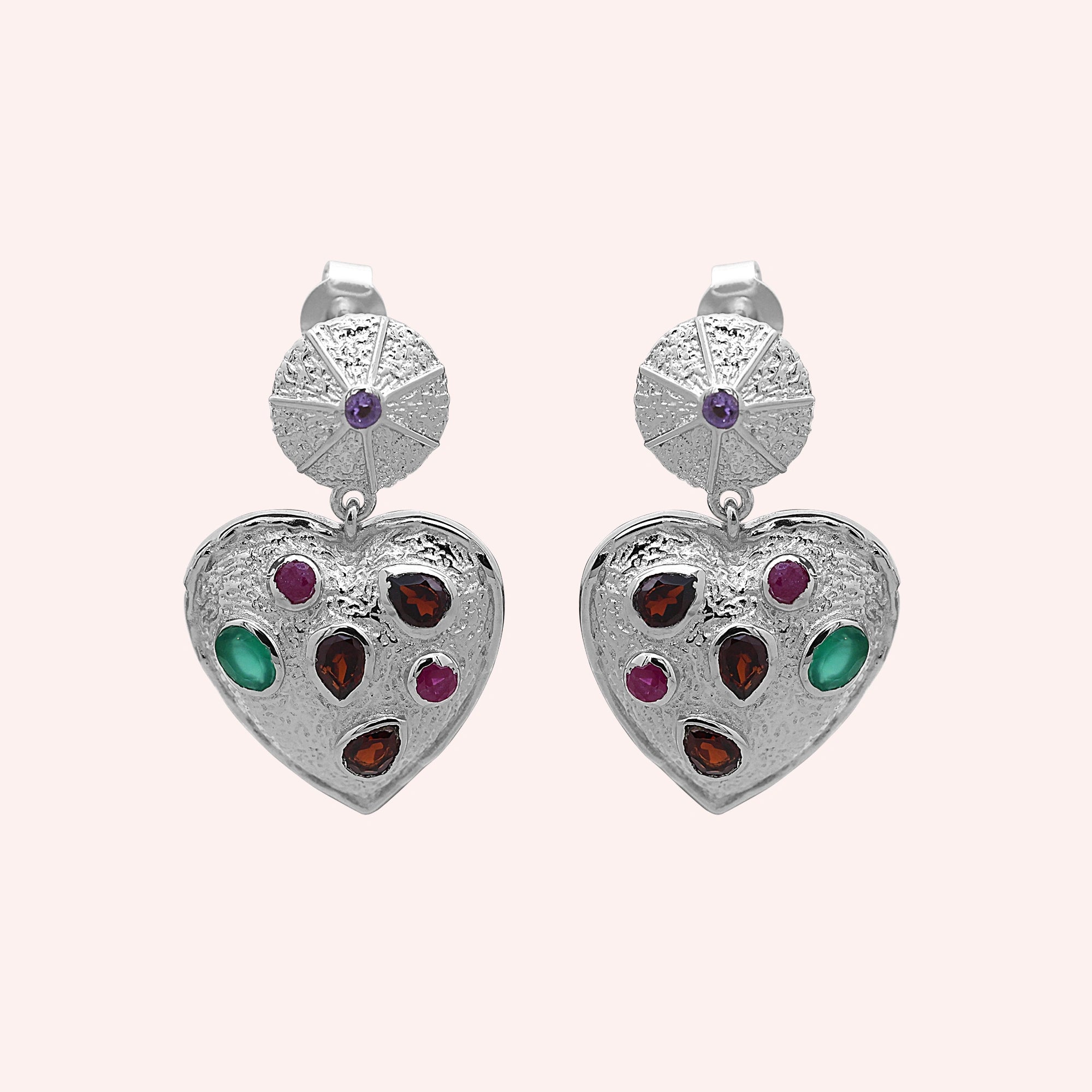 Heart_earrings_in_sterling_silver_with_garnet_ruby_and_green_onyx_stones_in_front_angle_on_solid_pink_background