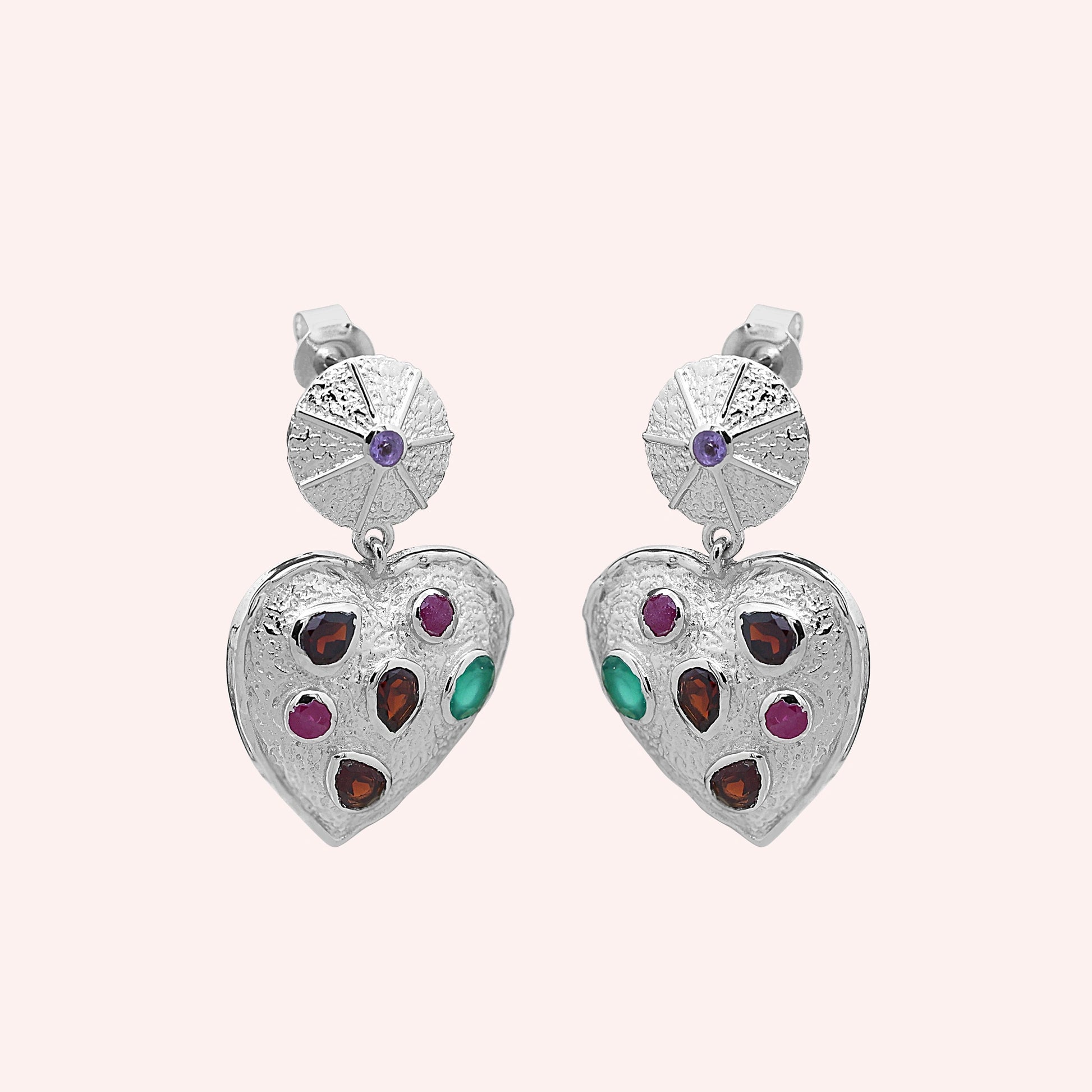 Heart_earrings_in_sterling_silver_with_garnet_ruby_and_green_onyx_stones_slightly_angled_on_solid_pink_background
