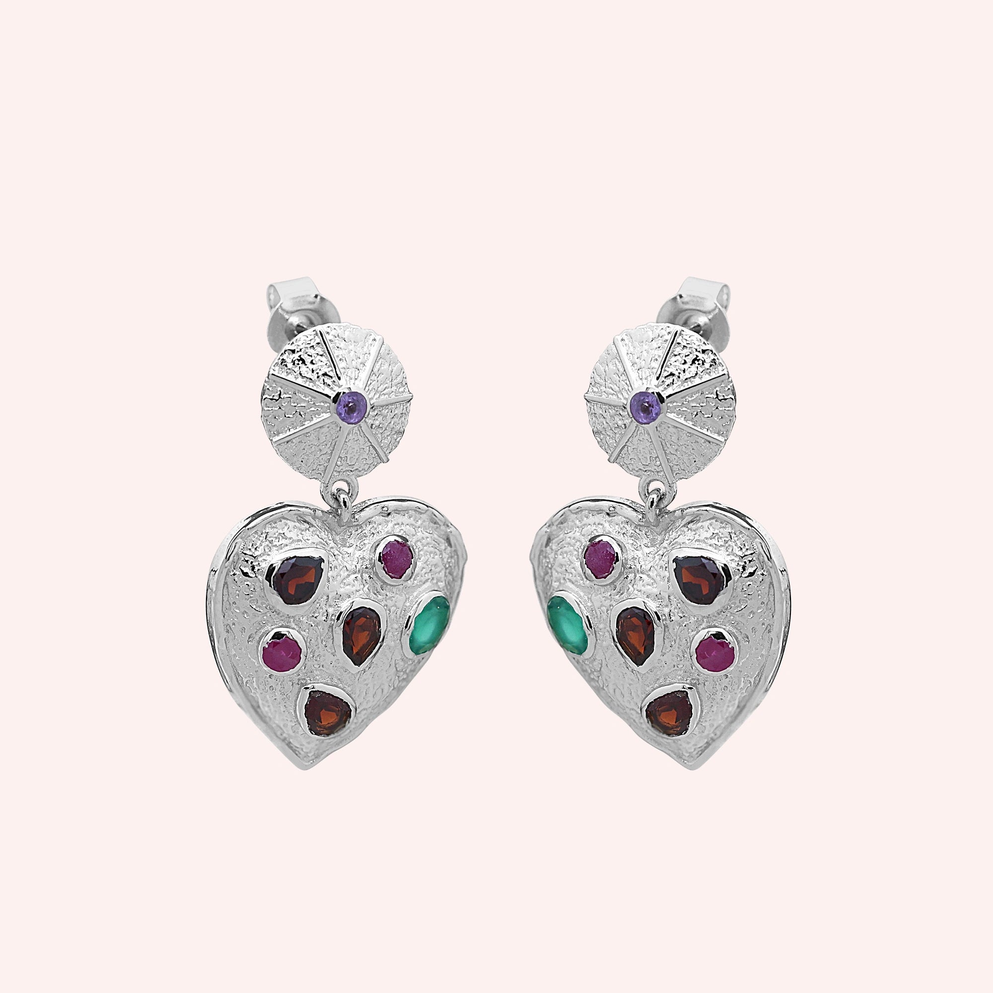 Heart_earrings_in_sterling_silver_with_garnet_ruby_and_green_onyx_stones_slightly_angled_on_solid_pink_background