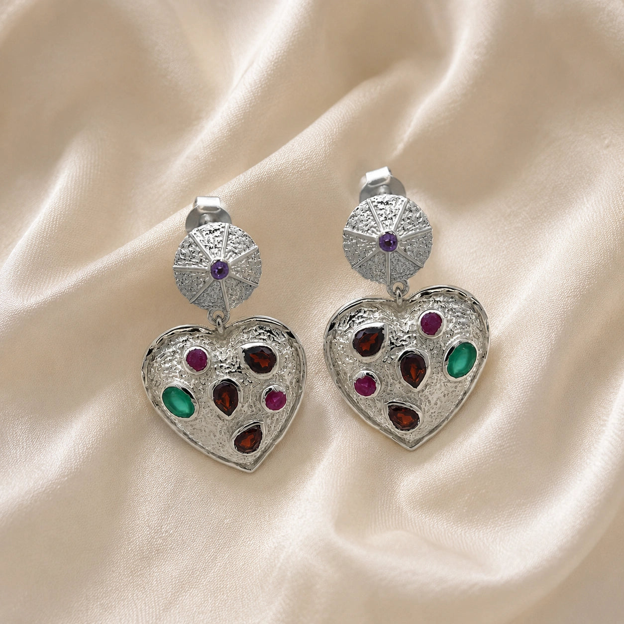 Heart_earrings_in_sterling_silver_with_garnet_ruby_and_green_onyx_stones_in_front_angle_on_soft_fabric_background