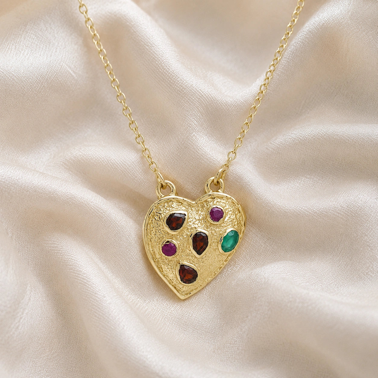 Heart_locket_necklace_gold_plated_silver_with_garnet_ruby_and_green_onyx_stones_in_slight_angle_view_on_soft_fabric_background