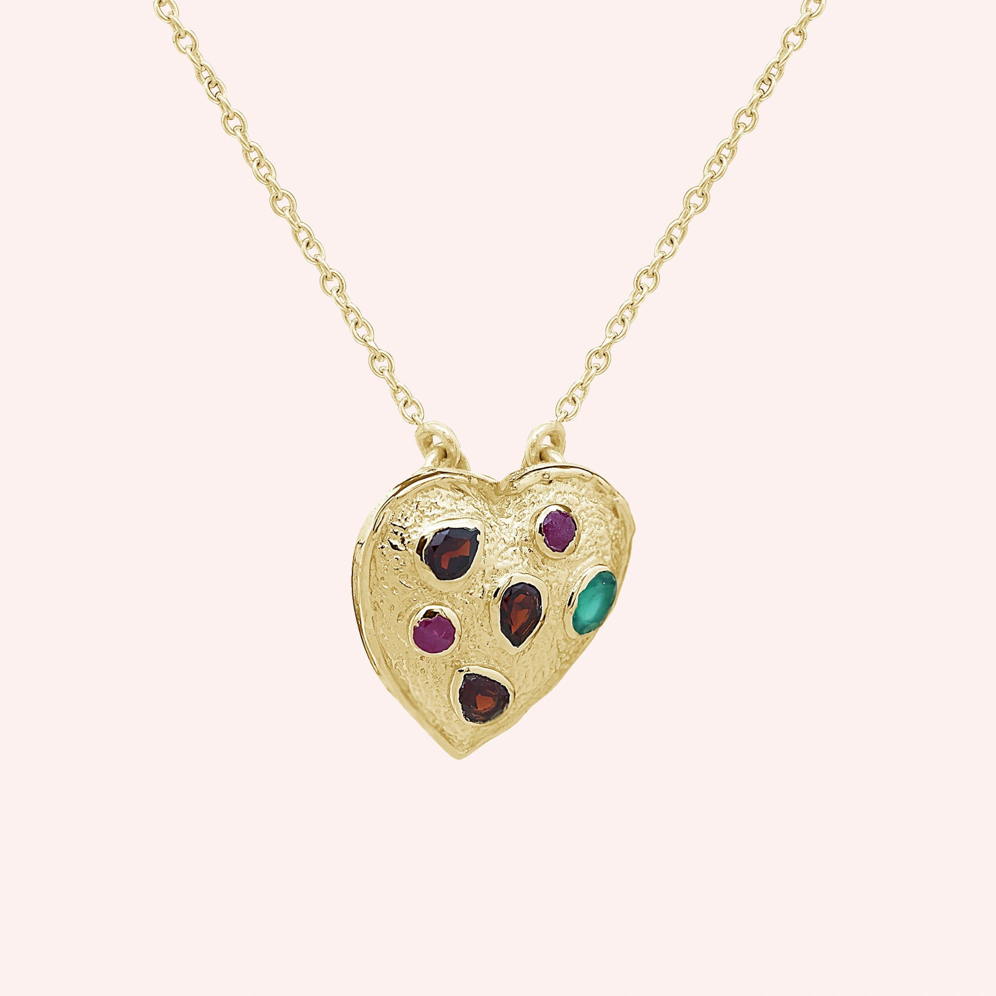 Heart_locket_necklace_gold_plated_silver_with_garnet_ruby_and_green_onyx_stones_in_slight_angle_view_on_solid_pink_background