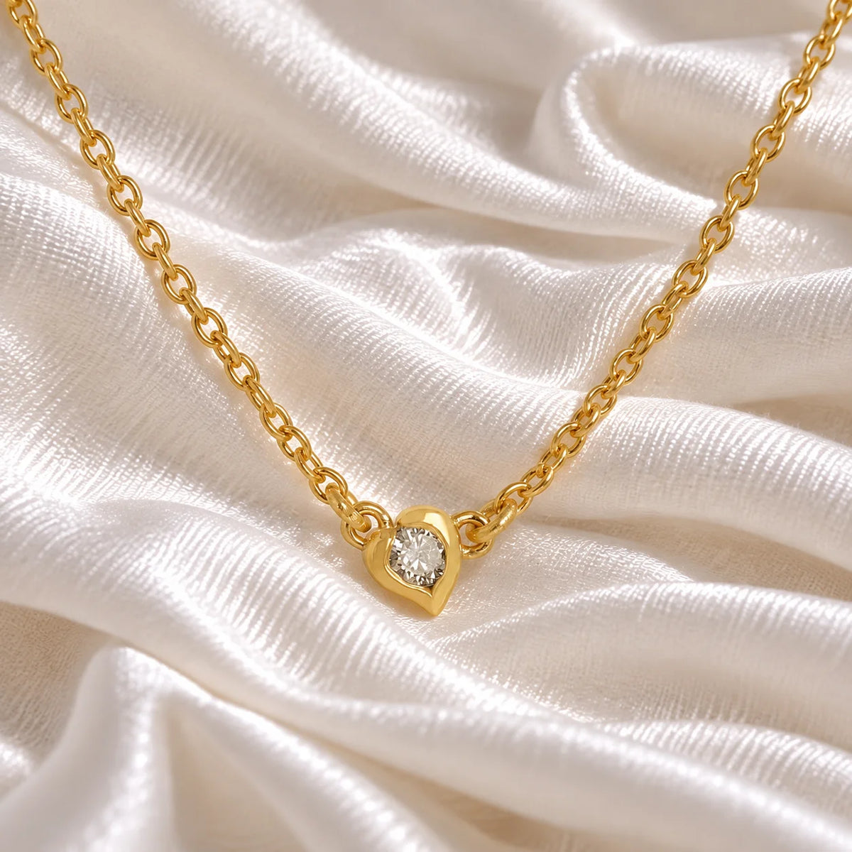 Heart_necklace_in_gold_plated_silver_with_a_small_round_lab_grown_diamond_at_front_angle_view_on_soft_fabric_background