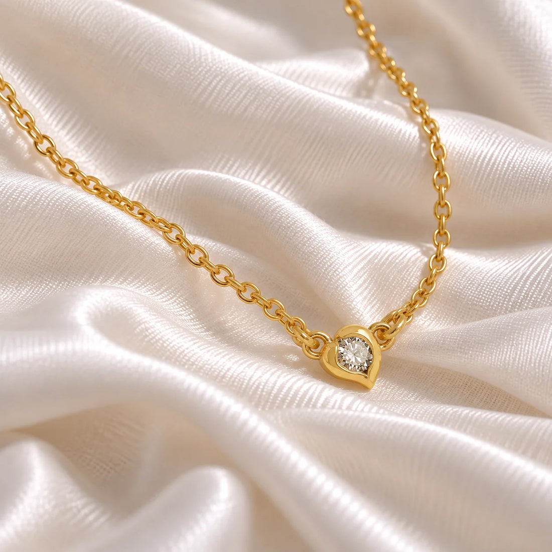 Heart_necklace_in_gold_plated_silver_with_a_small_round_lab_grown_diamond_at_side_angle_view_on_soft_fabric_background