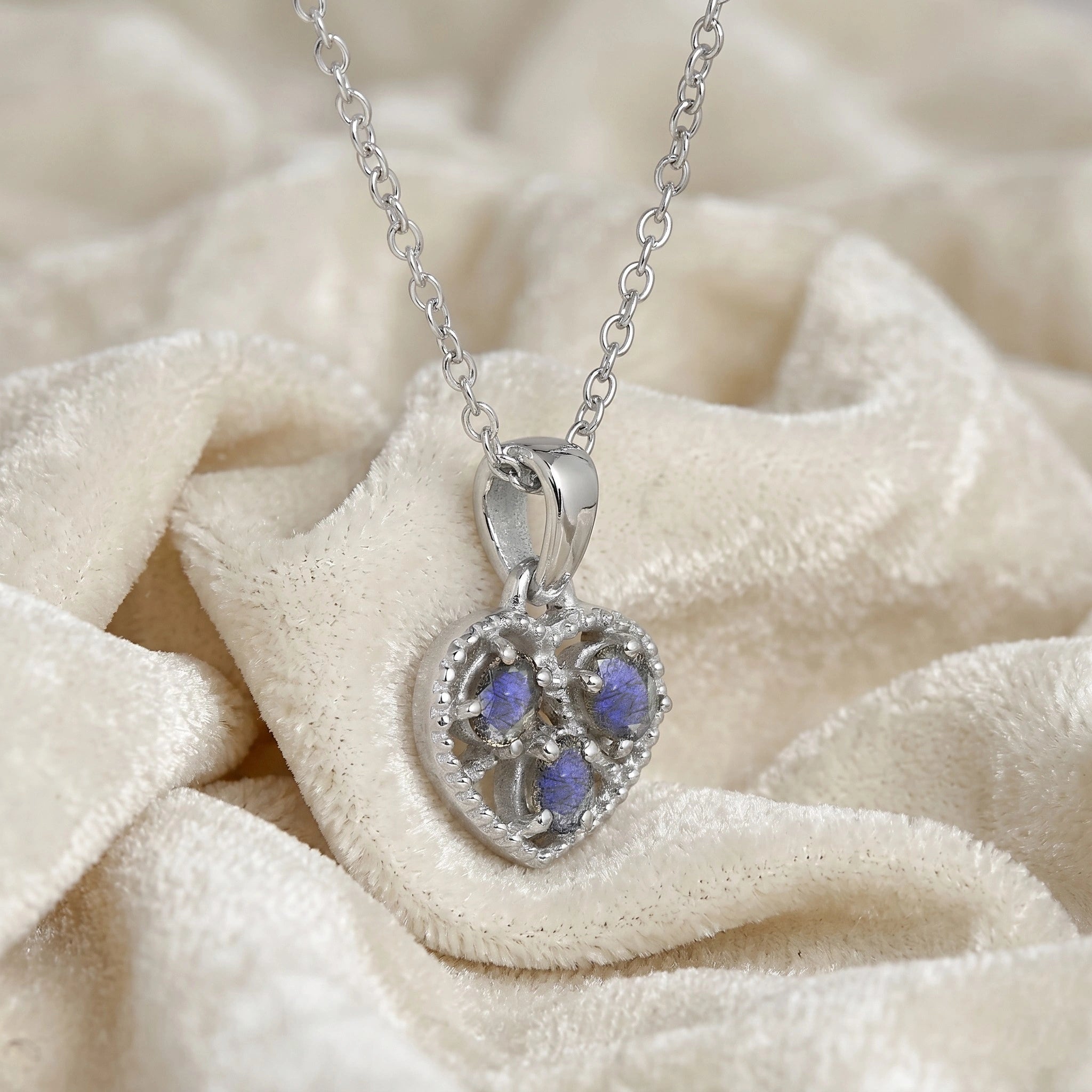 Heart_pendant_necklace_in_slightly_angled_view_with_sterling_silver_heart_and_labradorite_stones_on_soft_fabric_background