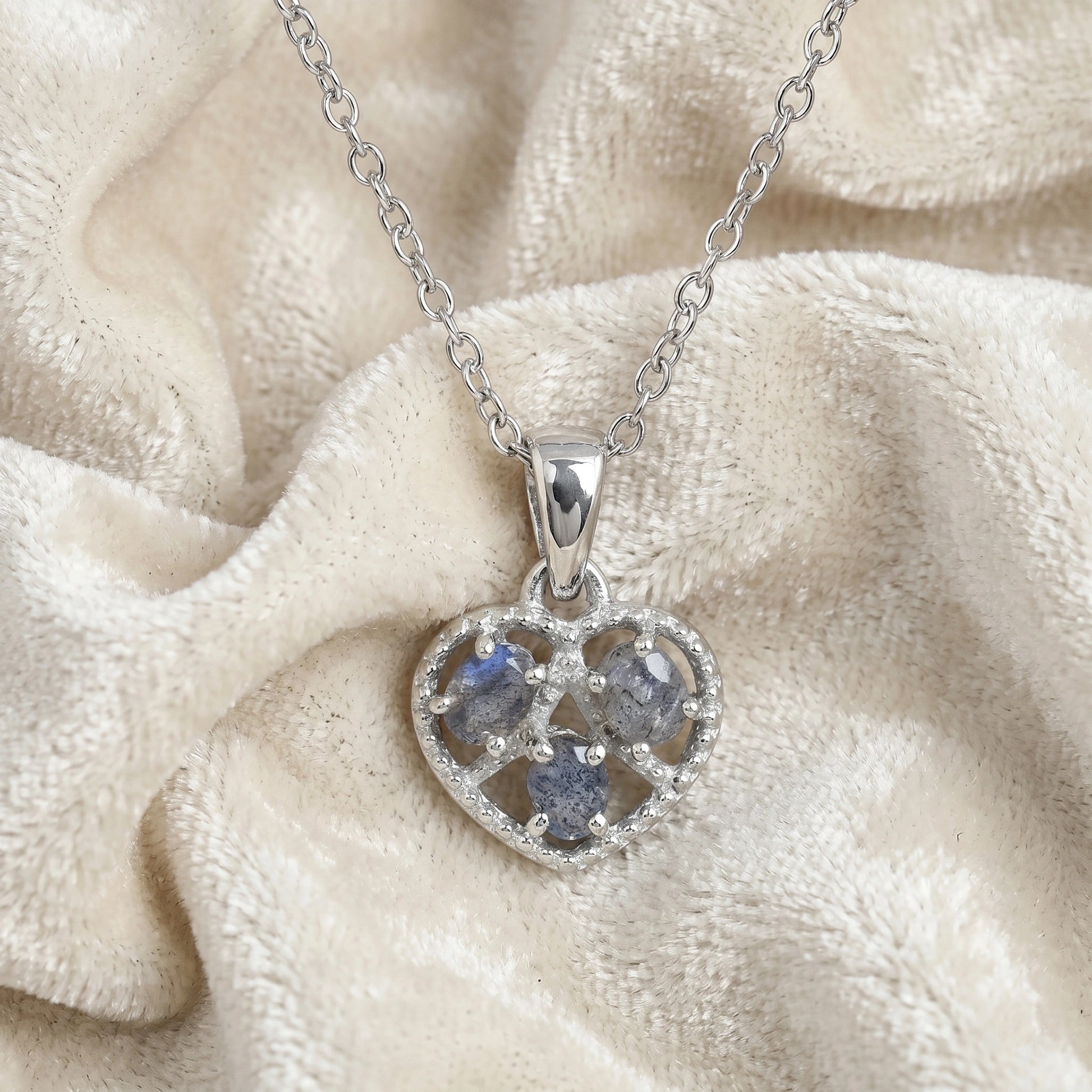 Heart_pendant_necklace_in_front_angled_view_with_sterling_silver_heart_and_labradorite_stones_on_soft_fabric_background