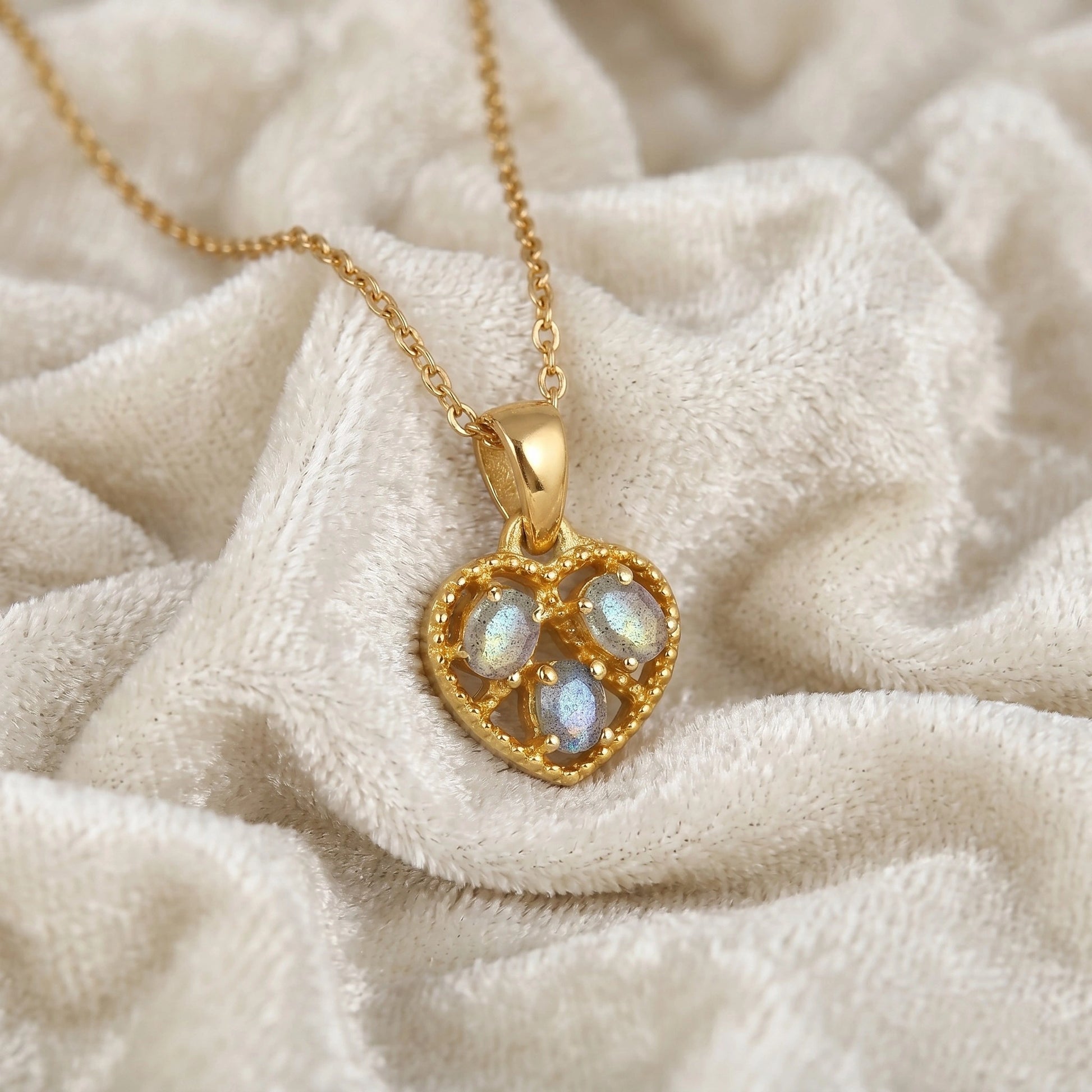 Heart_pendant_necklace_in_slightly_angled_view_with_gold_plated_silver_heart_and_labradorite_stones_on_soft_fabric_background