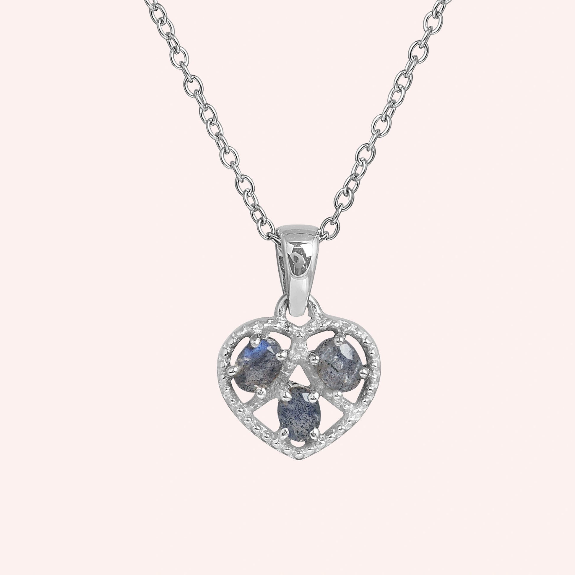 Heart_pendant_necklace_in_front_angled_view_with_sterling_silver_heart_and_labradorite_stones_on_solid_pink_background