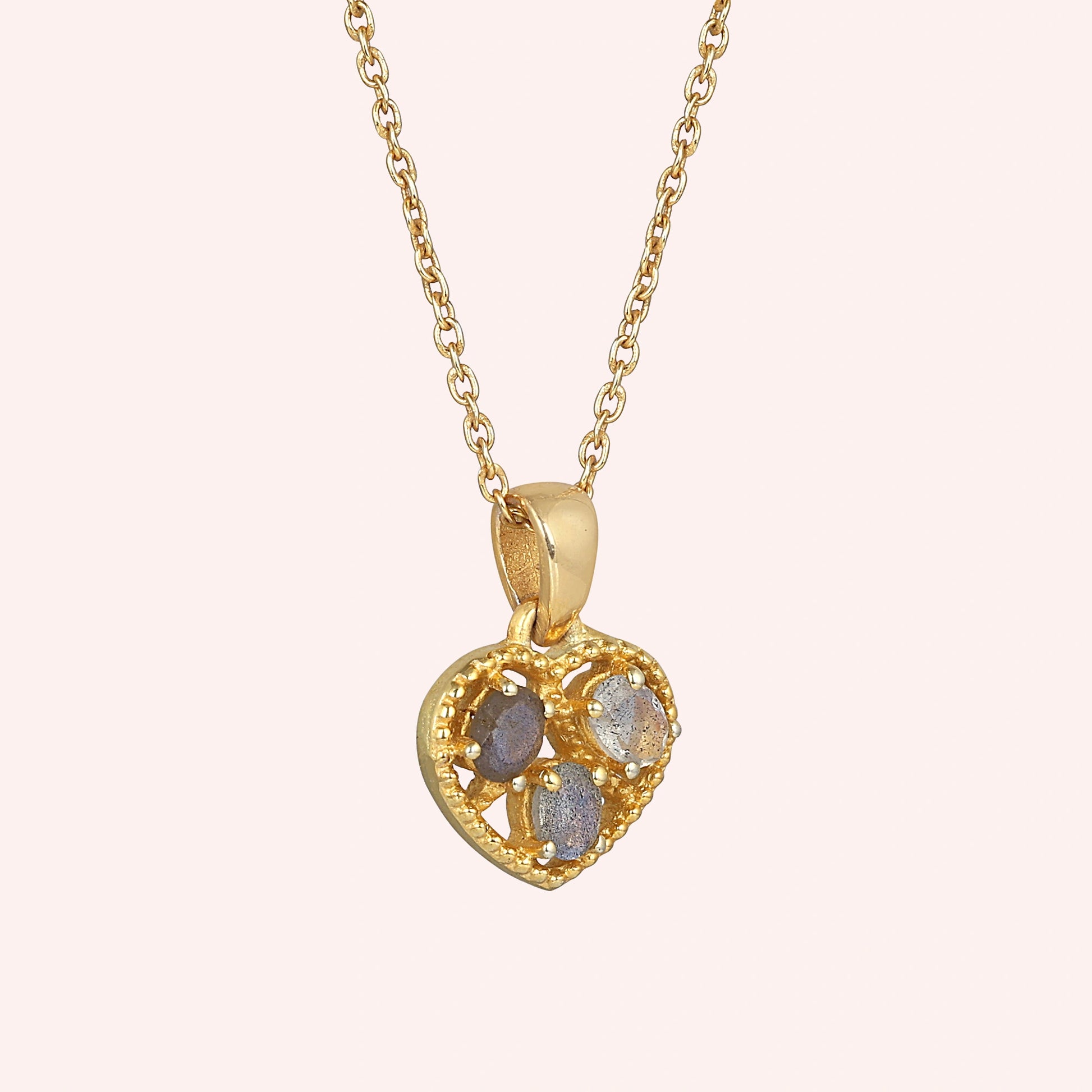 Heart_pendant_necklace_in_slightly_angled_view_with_gold_plated_silver_heart_and_labradorite_stones_on_solid_pink_background