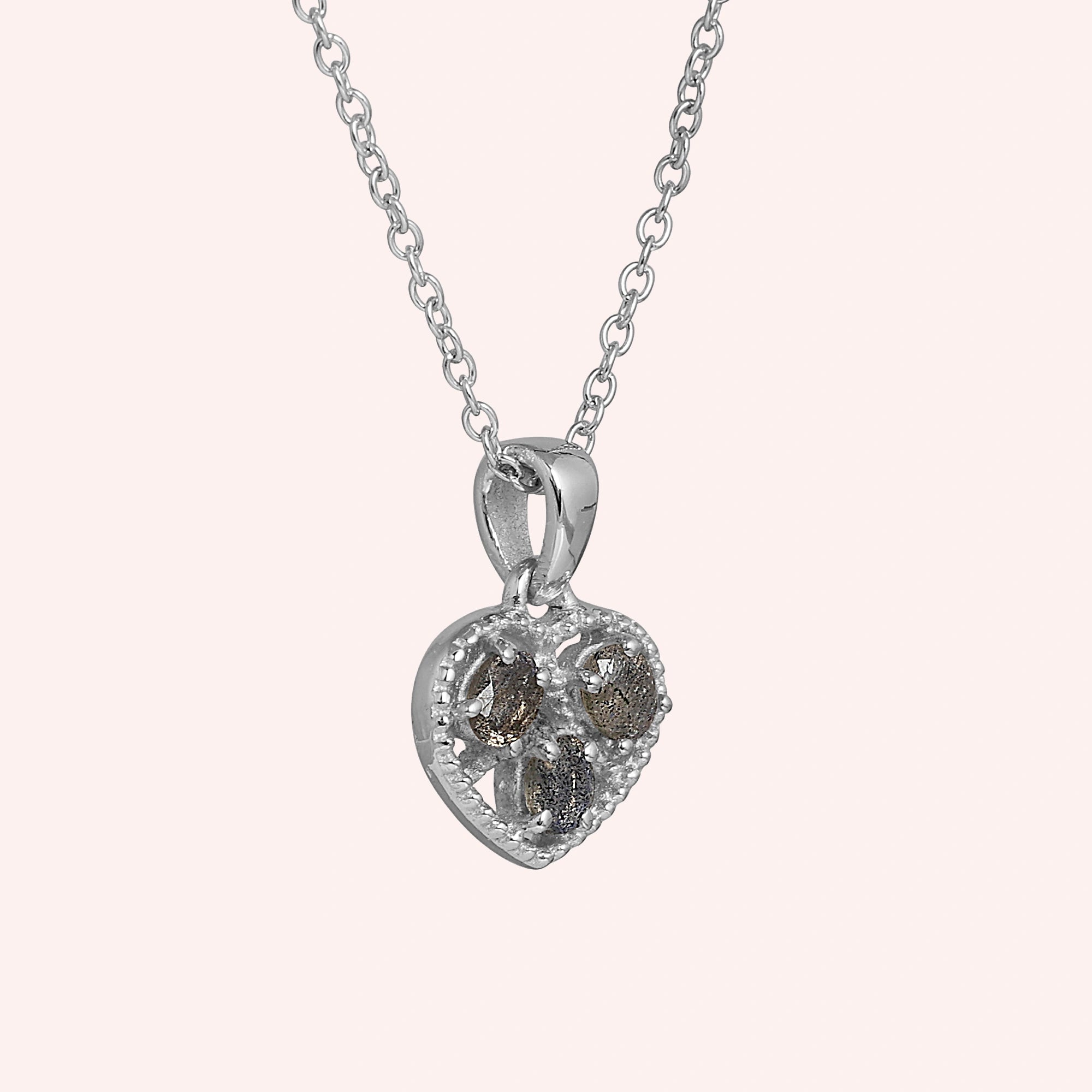 Heart_pendant_necklace_in_slightly_angled_view_with_sterling_silver_heart_and_labradorite_stones_on_solid_pink_background