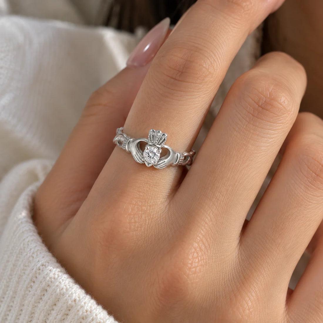 Heart_ring_in_gold_plated_silver_with_a_hand_a_heart_and_a_crown_design_at_front_angle_view_on_soft_fabric_background