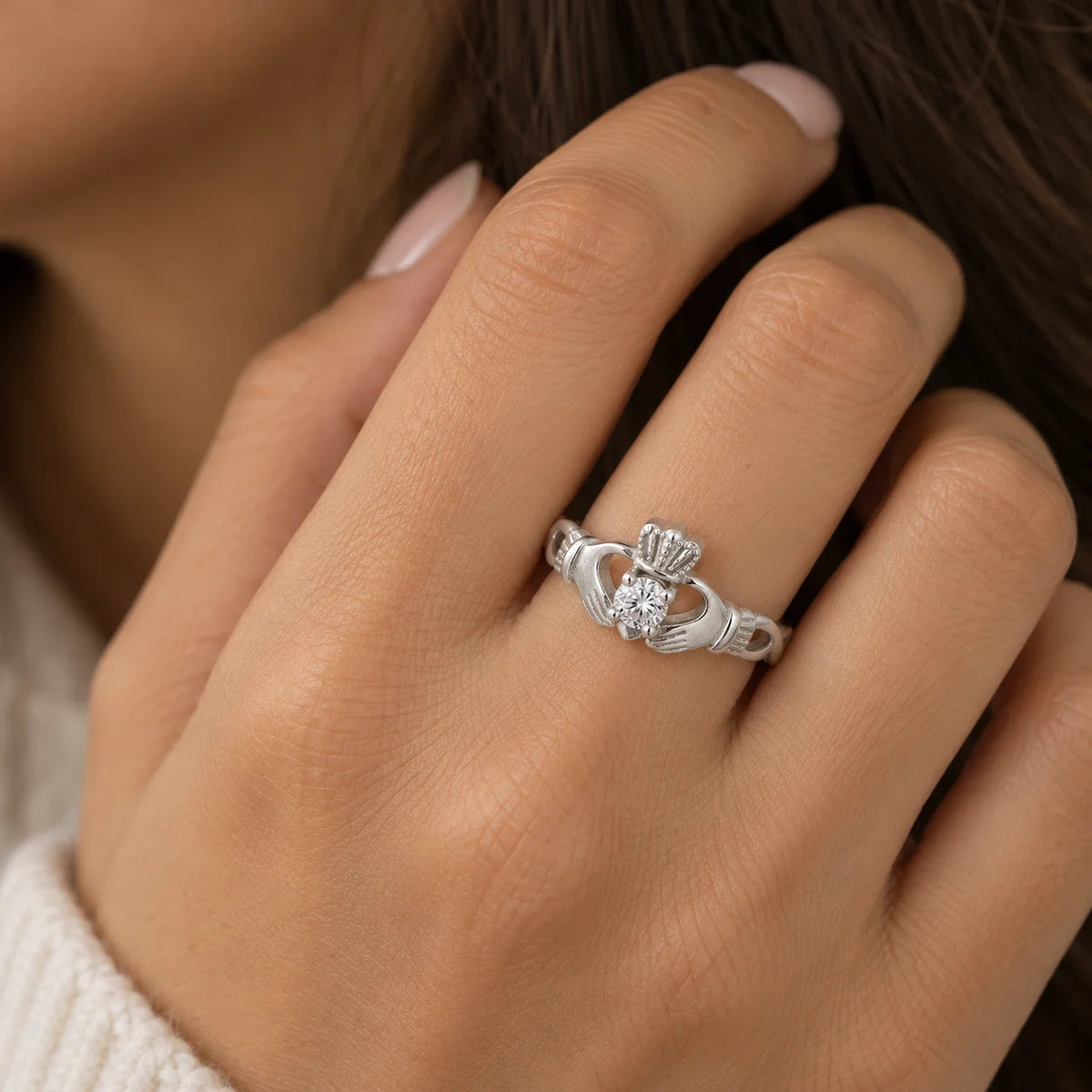Heart_ring_in_sterling_silver_with_a_hand_a_heart_and_a_crown_design_at_front_angle_view_on_worn_by_a_model