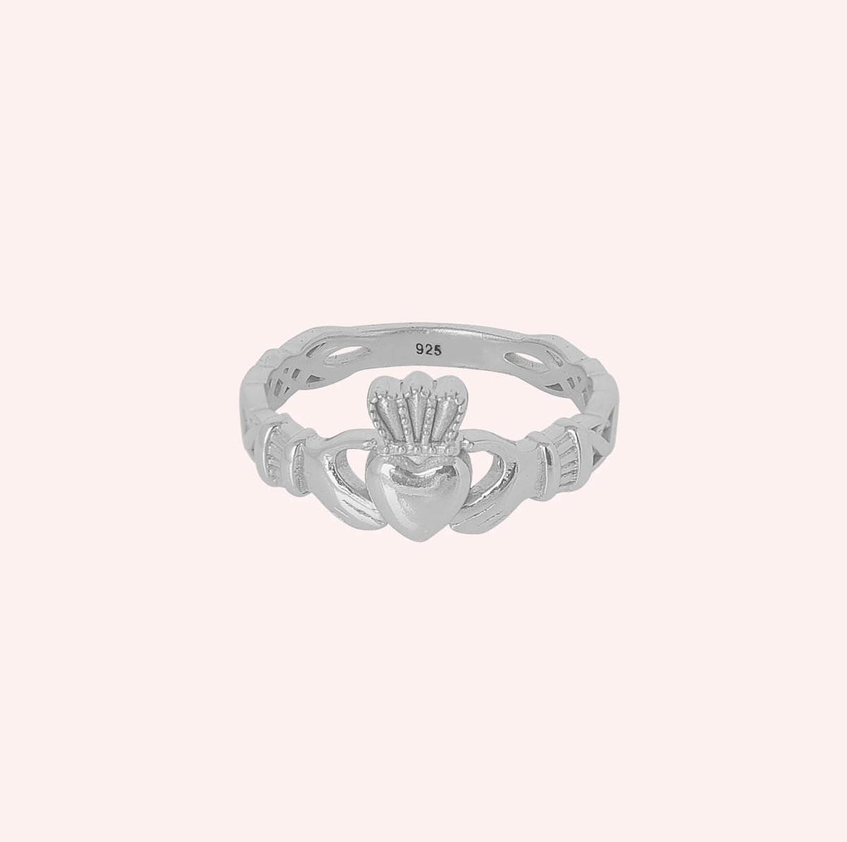 Heart_ring_in_sterling_silver_with_a_heart_hand_and_crown_design_at_front_angle_view_on_solid_pink_background
