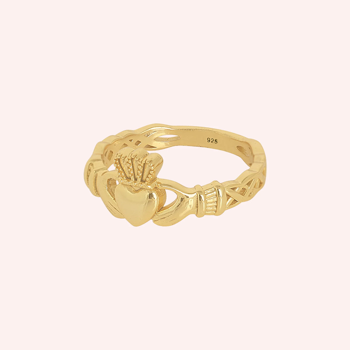 Heart_ring_in_gold_plated_silver_with_a_heart_hand_and_crown_design_at_slight_angle_view_on_solid_pink_background