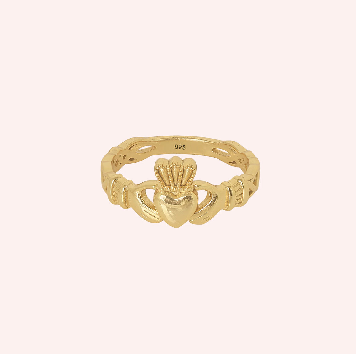 Heart_ring_in_gold_plated_silver_with_a_heart_hand_and_crown_design_at_front_angle_view_on_solid_pink_background