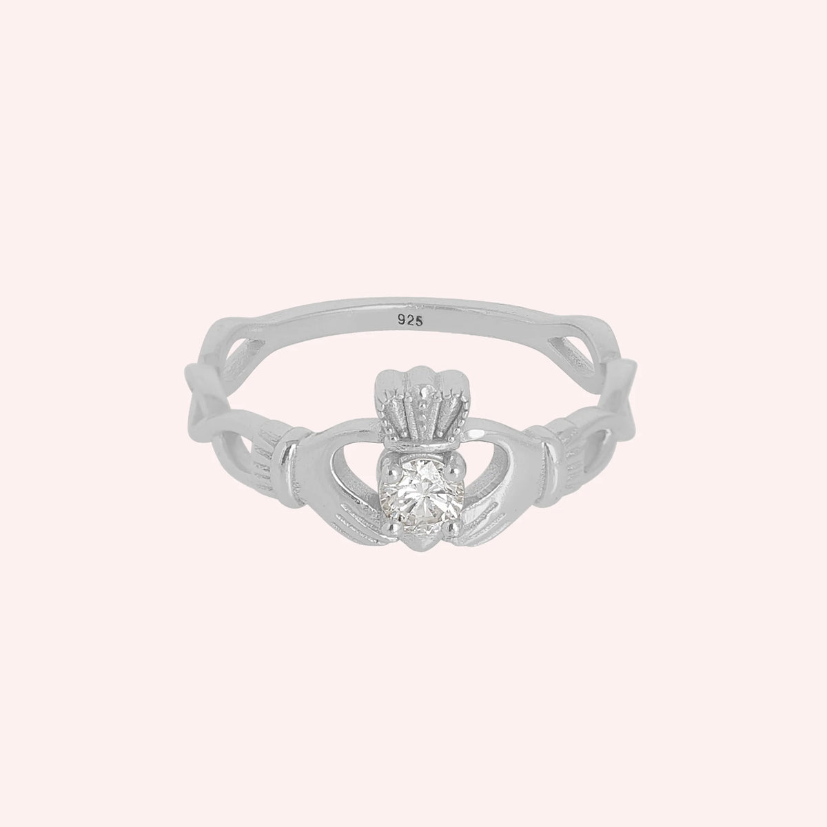 Heart_ring_in_sterling_silver_with_a_hand_a_heart_and_a_crown_design_at_front_angle_view_on_solid_pink_background
