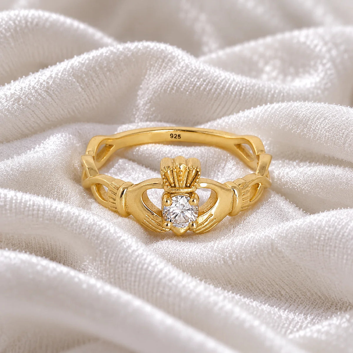 Heart_ring_in_gold_plated_silver_with_a_hand_a_heart_and_a_crown_design_at_front_angle_view_on_soft_fabric_background