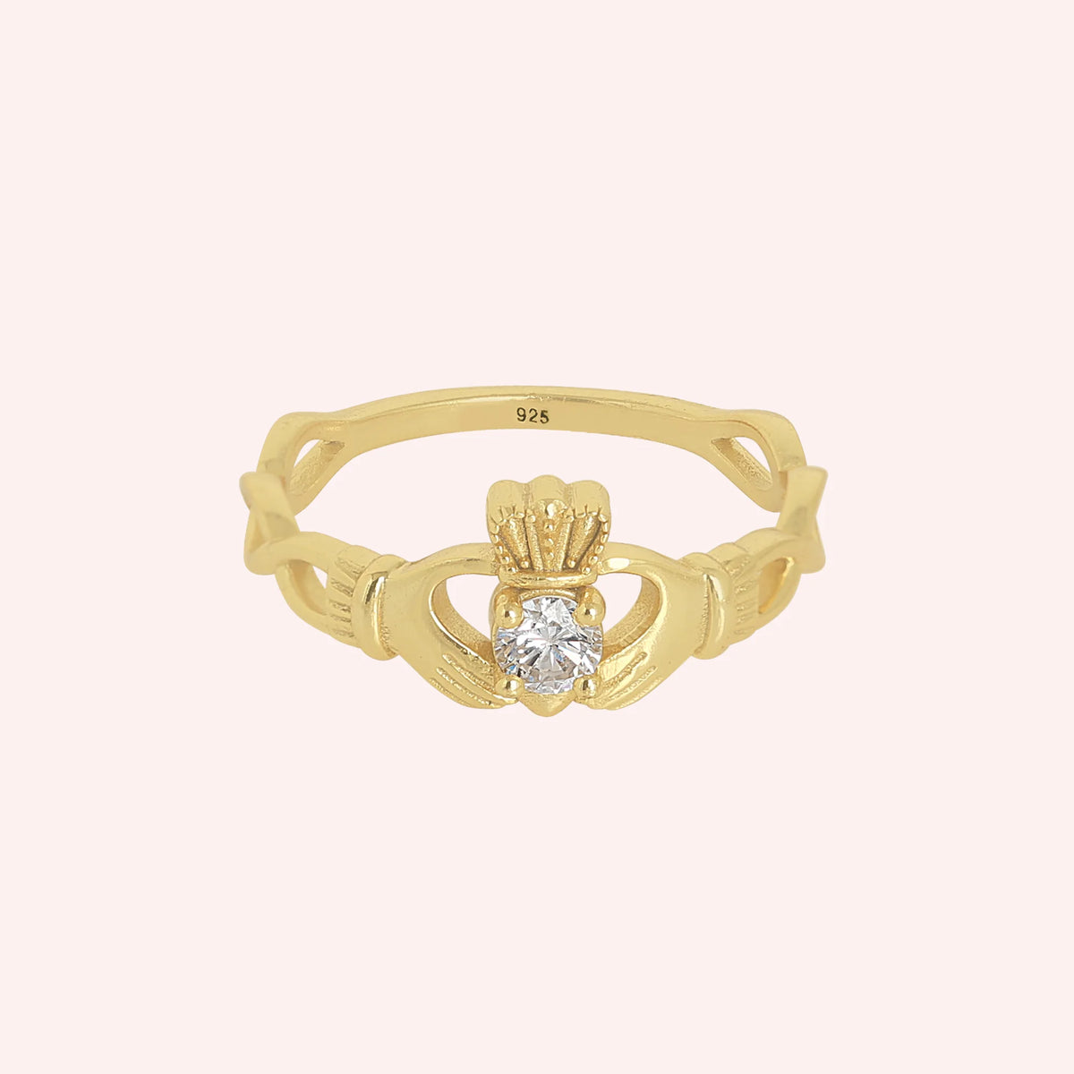 Heart_ring_in_gold_plated_silver_with_a_hand_a_heart_and_a_crown_design_at_front_angle_view_on_solid_pink_background