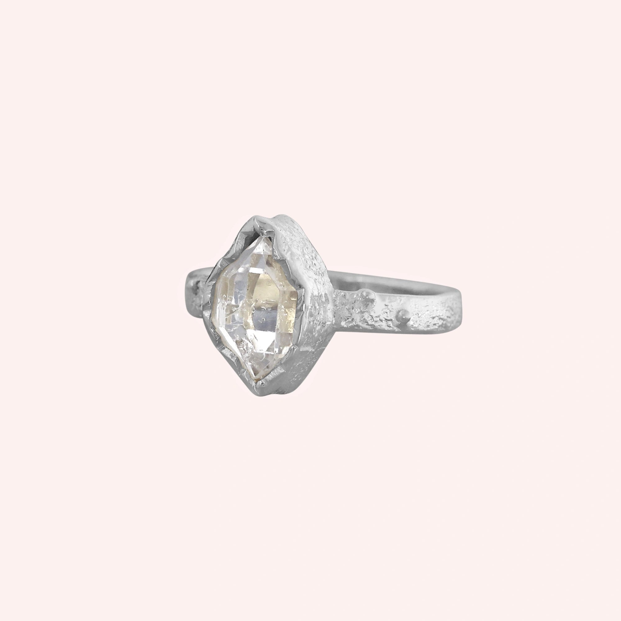 Herkimer_diamond_ring_sterling_silver_band_with_raw_herkimer_stone_shown_in_slightly_angled_view_on_solid_pink_background