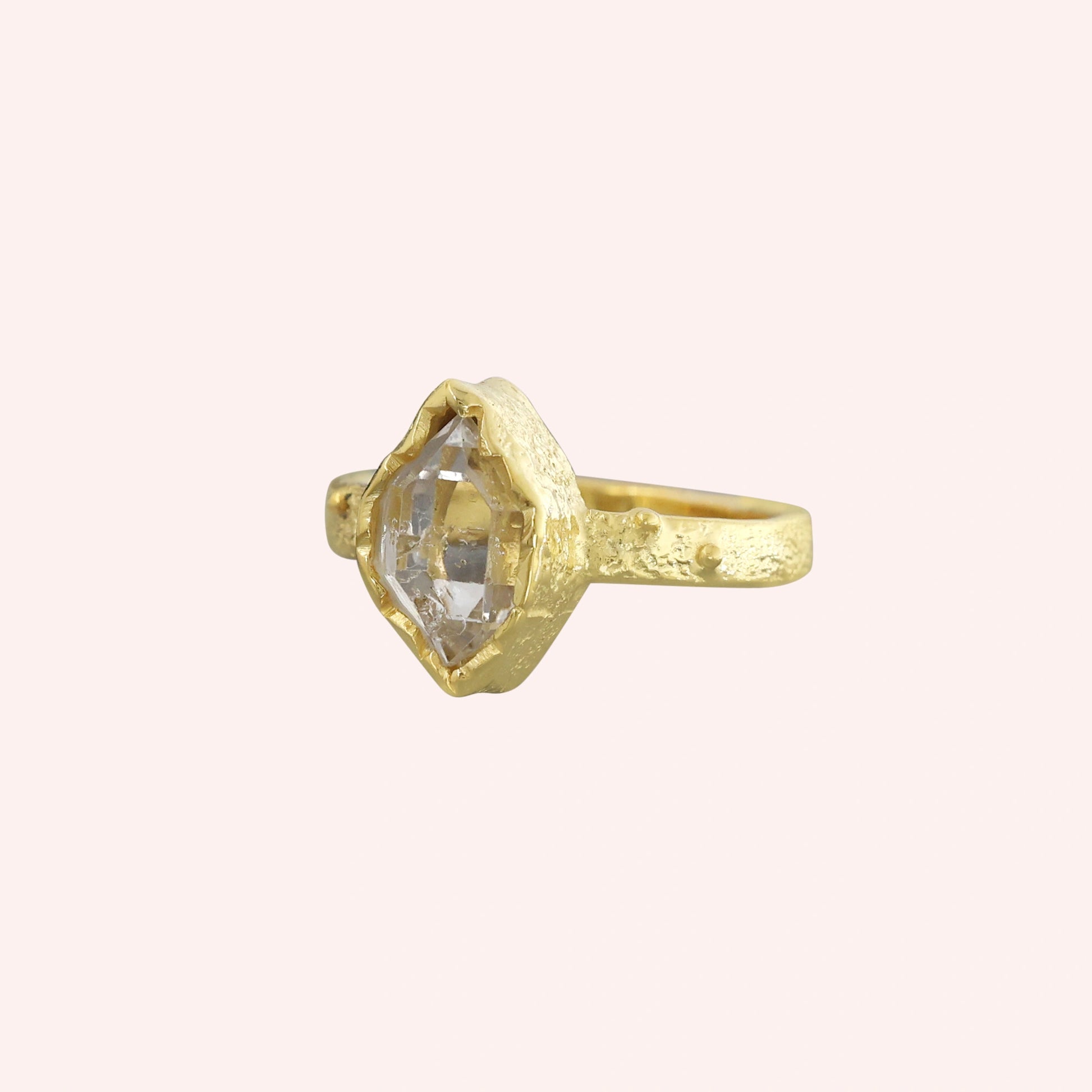 Herkimer_diamond_ring_gold_plated_silver_band_with_raw_herkimer_stone_shown_in_slightly_angled_view_on_solid_pink_background