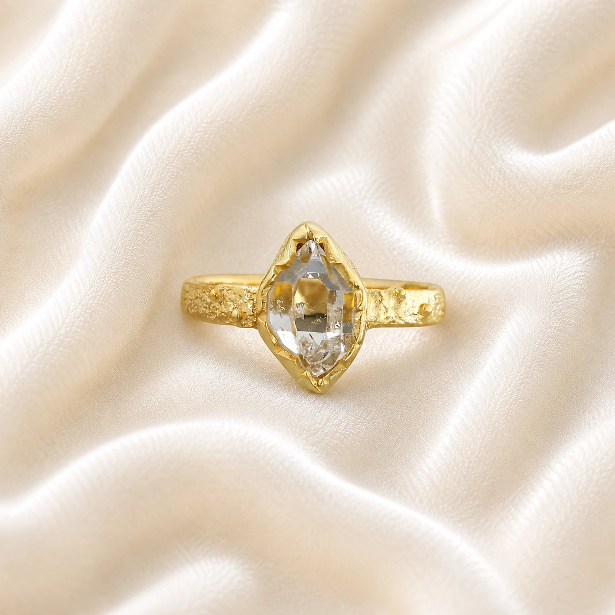 Herkimer_diamond_ring_gold_plated_silver_band_with_raw_herkimer_stone_shown_in_front_angle_on_soft_fabric_background