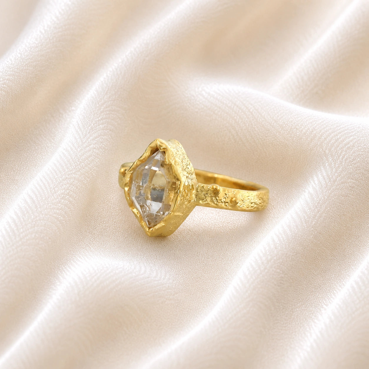 Herkimer_diamond_ring_gold_plated_silver_band_with_raw_herkimer_stone_shown_in_slightly_angled_view_on_soft_fabric_background