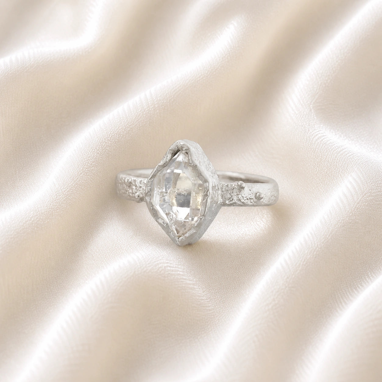 Herkimer_diamond_ring_sterling_silver_band_with_raw_herkimer_stone_shown_in_slightly_angled_view_on_soft_fabric_background