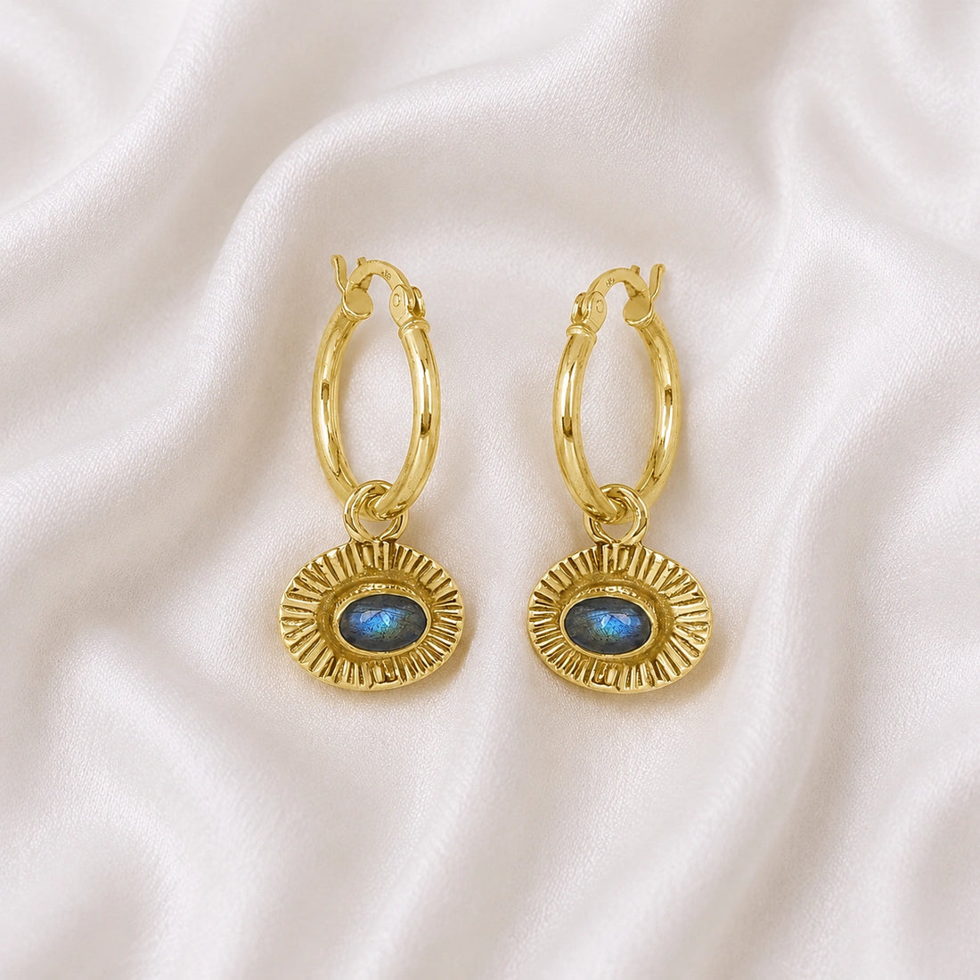 Hoop_earrings_in_gold_plated_silver_with_oval_labradorite_stone_at_front_angle_view_on_soft_fabric_background