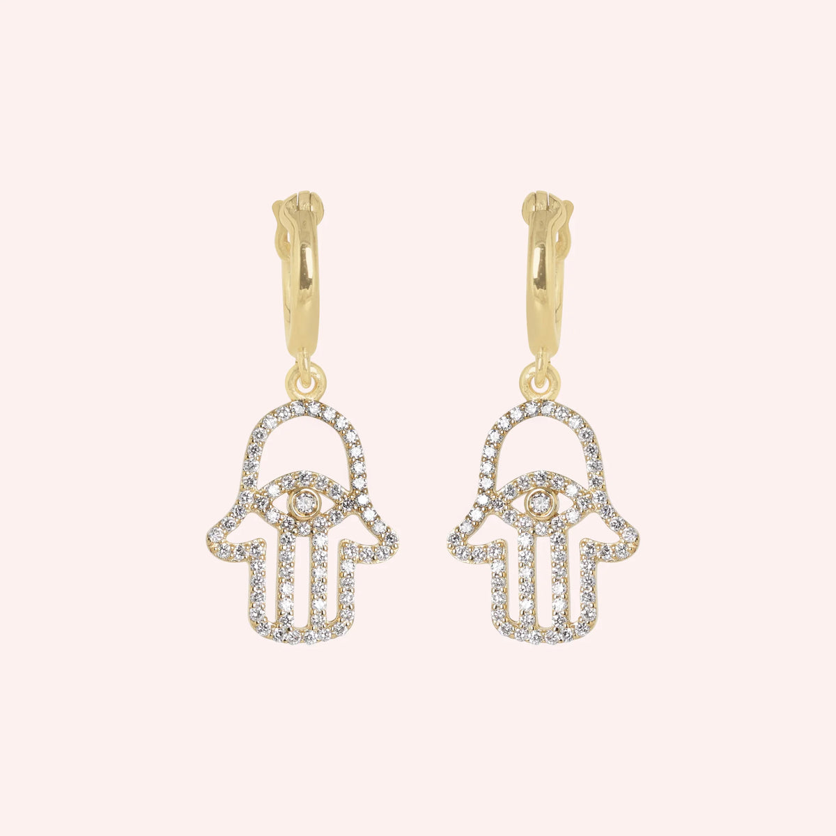 Hoop_earrings_in_gold_plated_silver_with_hamsa_hand_design_and_CZ_stones_at_front_angle_view_on_solid_pink_background