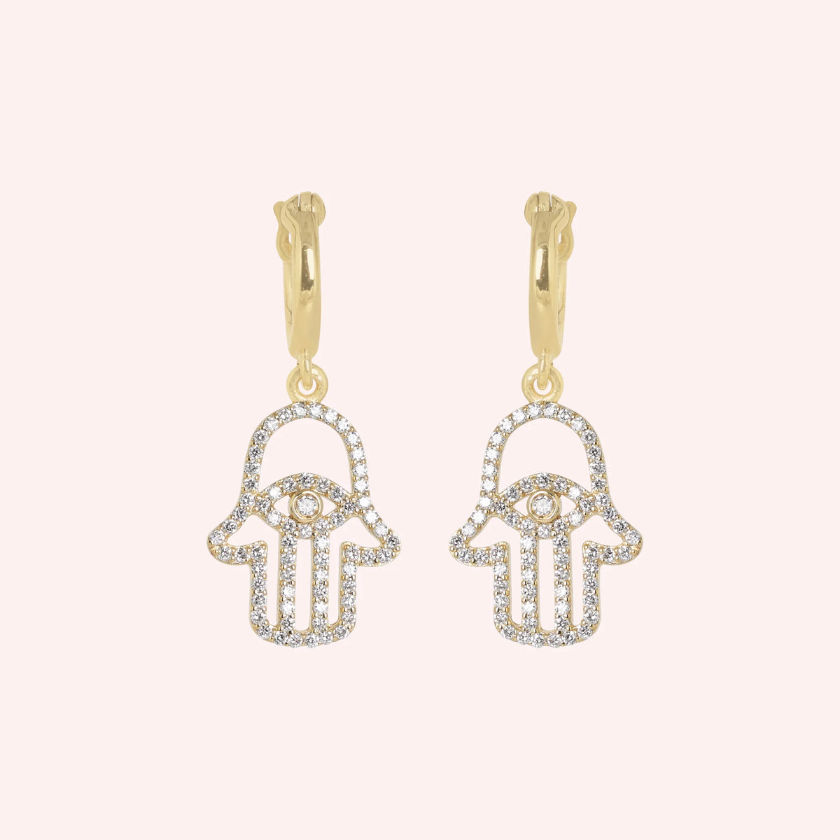 Hoop_earrings_in_gold_plated_silver_with_a_hamsa_hand_design_at_front_angle_view_on_solid_pink_background