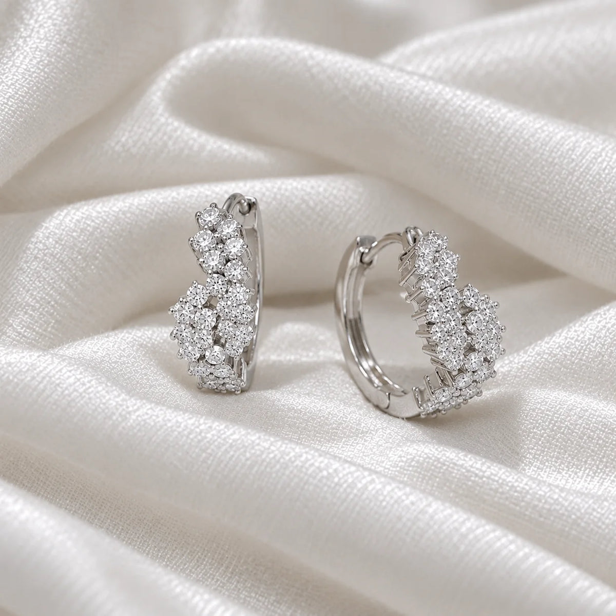 Huggie_earrings_in_sterling_silver_with_lab_grown_diamonds_at_side_angle_view_on_soft_fabric_background