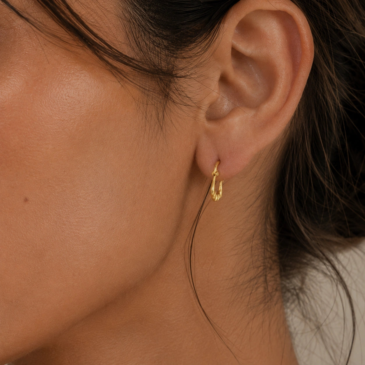 Huggie_earrings_in_gold_plated_silver_with_handcrafted_teardrop_hoops_worn_by_a_model