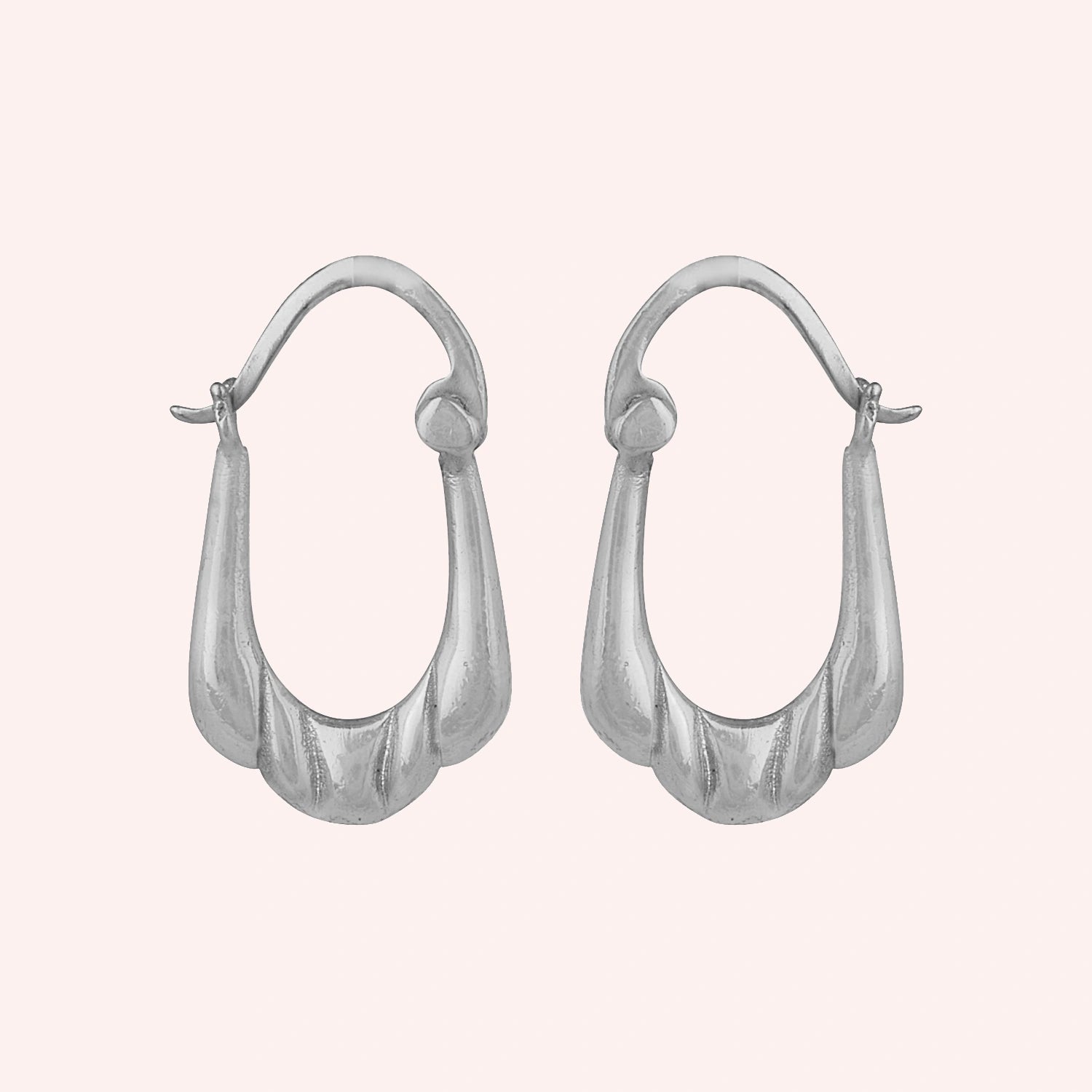 Huggie_earrings_in_sterling_silver_with_handcrafted_teardrop_hoops_at_front_angle_on_solid_pink_background