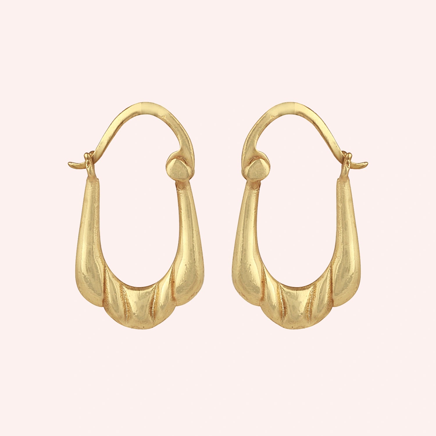 Huggie_earrings_in_gold_plated_silver_with_handcrafted_teardrop_hoops_at_front_angle_on_solid_pink_background