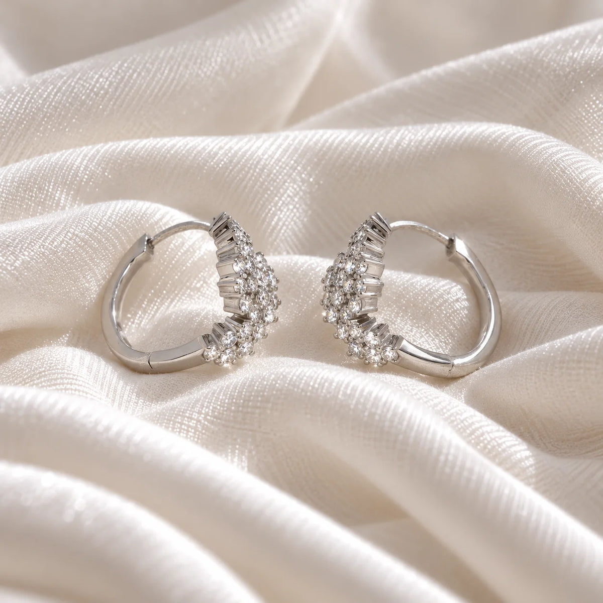Huggie_earrings_in_sterling_silver_with_lab_grown_diamonds_at_slight_angle_view_on_soft_fabric_background