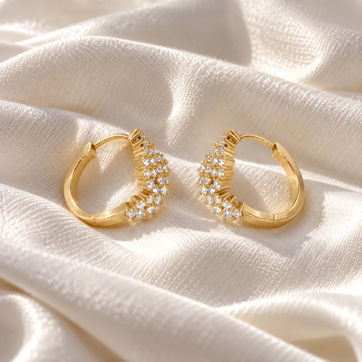 Huggie_earrings_in_gold_plated_silver_with_lab_grown_diamonds_at_slight_angle_view_on_soft_fabric_background