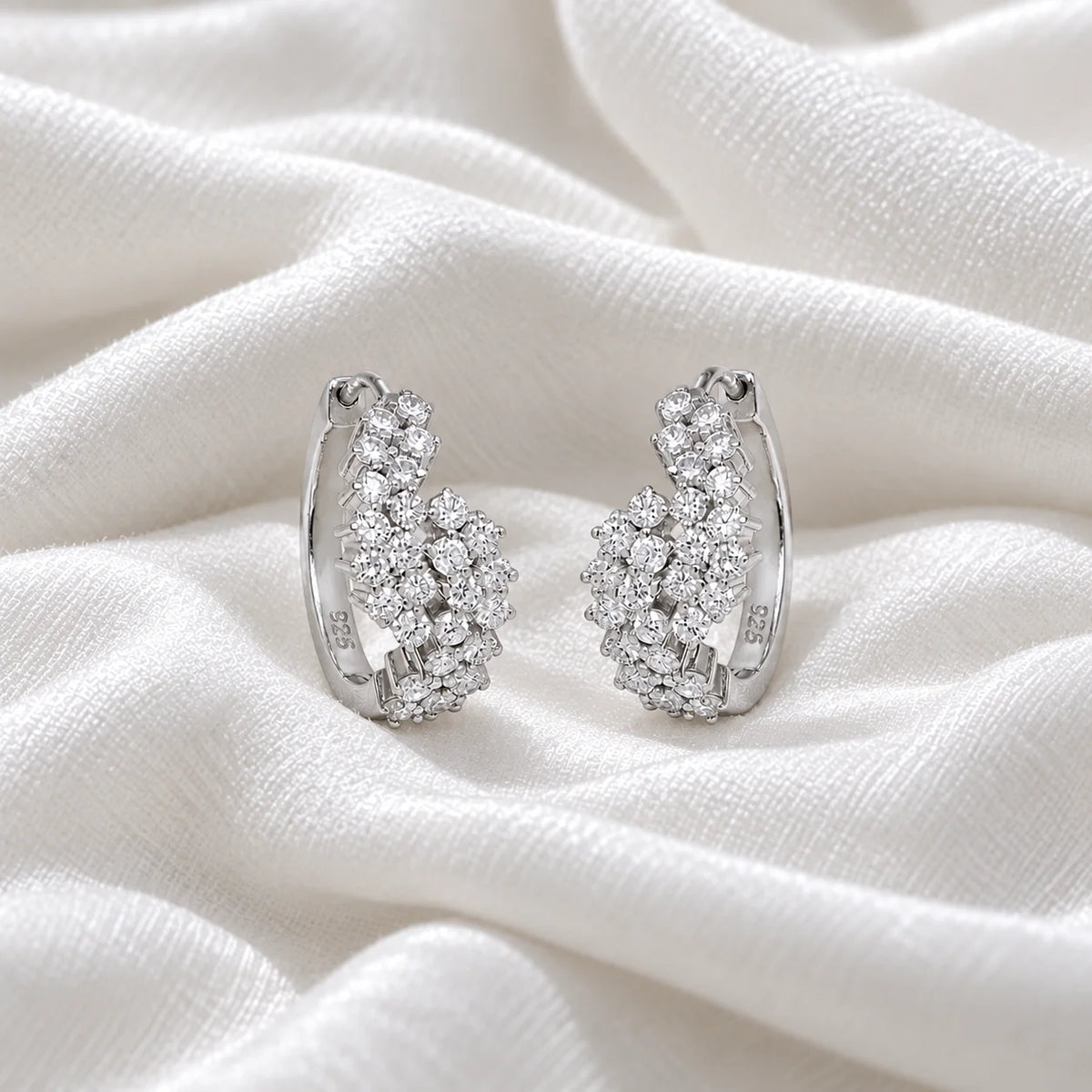 Huggie_earrings_in_sterling_silver_with_lab_grown_diamonds_at_front_angle_view_on_soft_fabric_background