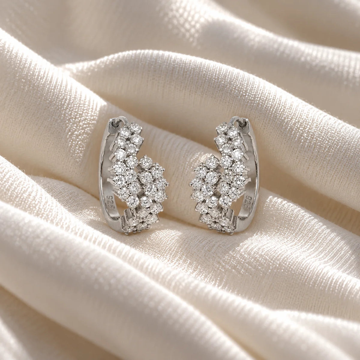 Huggie_earrings_in_sterling_silver_with_lab_grown_diamonds_at_front_angle_view_on_soft_fabric_background