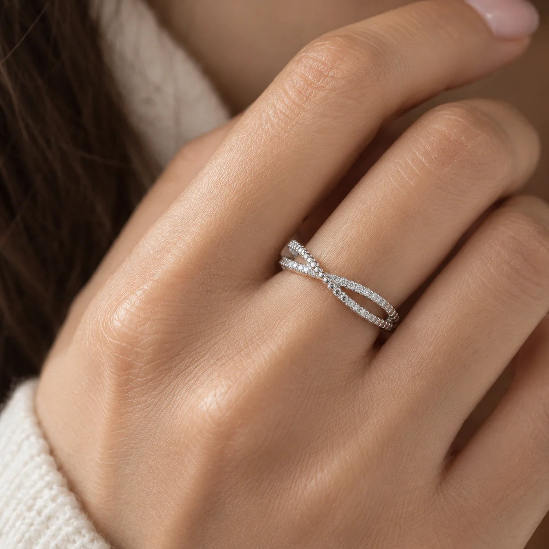 Infinity_ring_in_gold_plated_silver_with_criss_cross_design_and_lab_grown_diamonds_at_front_angle_view_on_soft_fabric_background