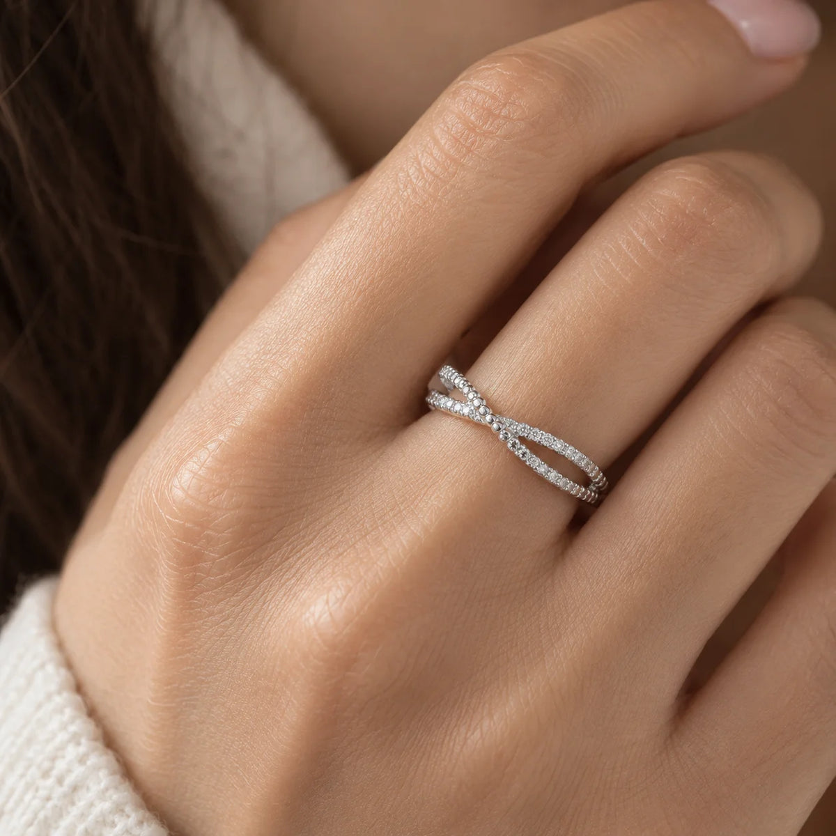 Infinity_ring_in_sterling_silver_with_criss_cross_design_and_lab_grown_diamonds_at_front_angle_view_worn_by_a_model